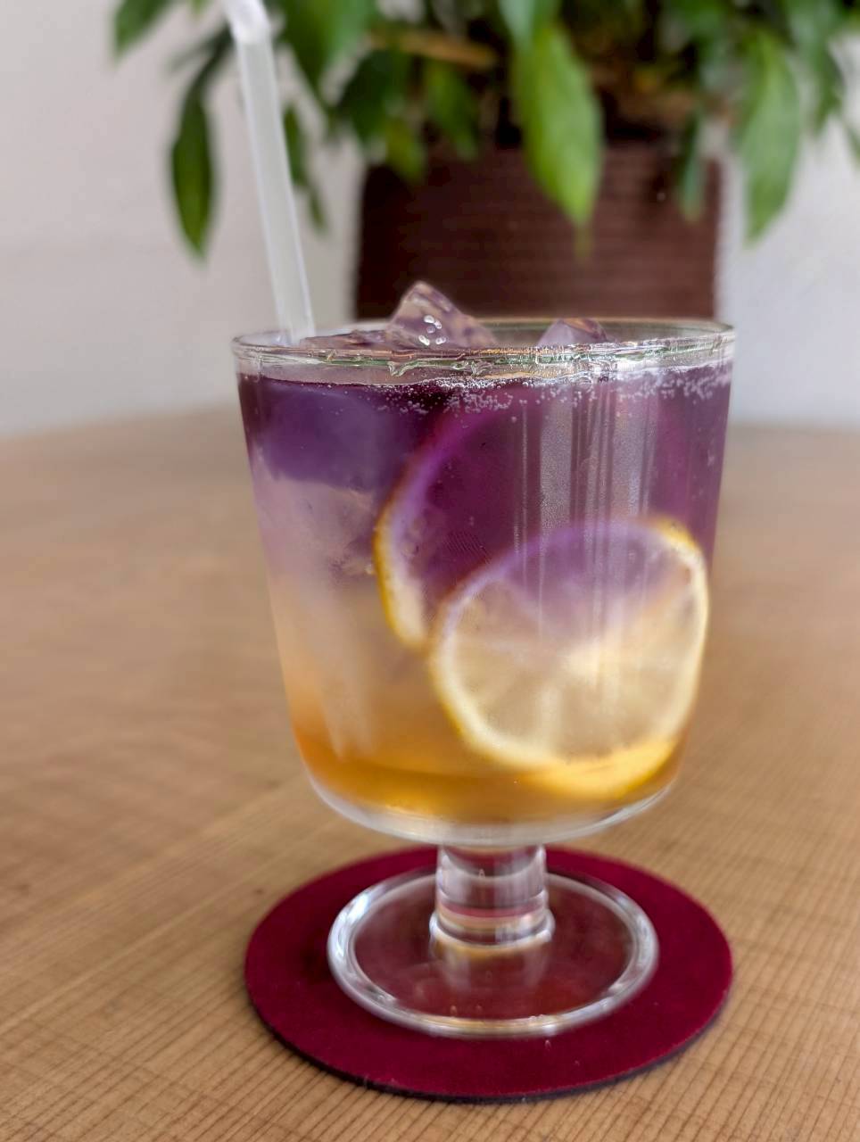 Vivid purple butterfly-pea lemonade with floating lemon slices in a stemmed glass — Focaccino Hakuba
