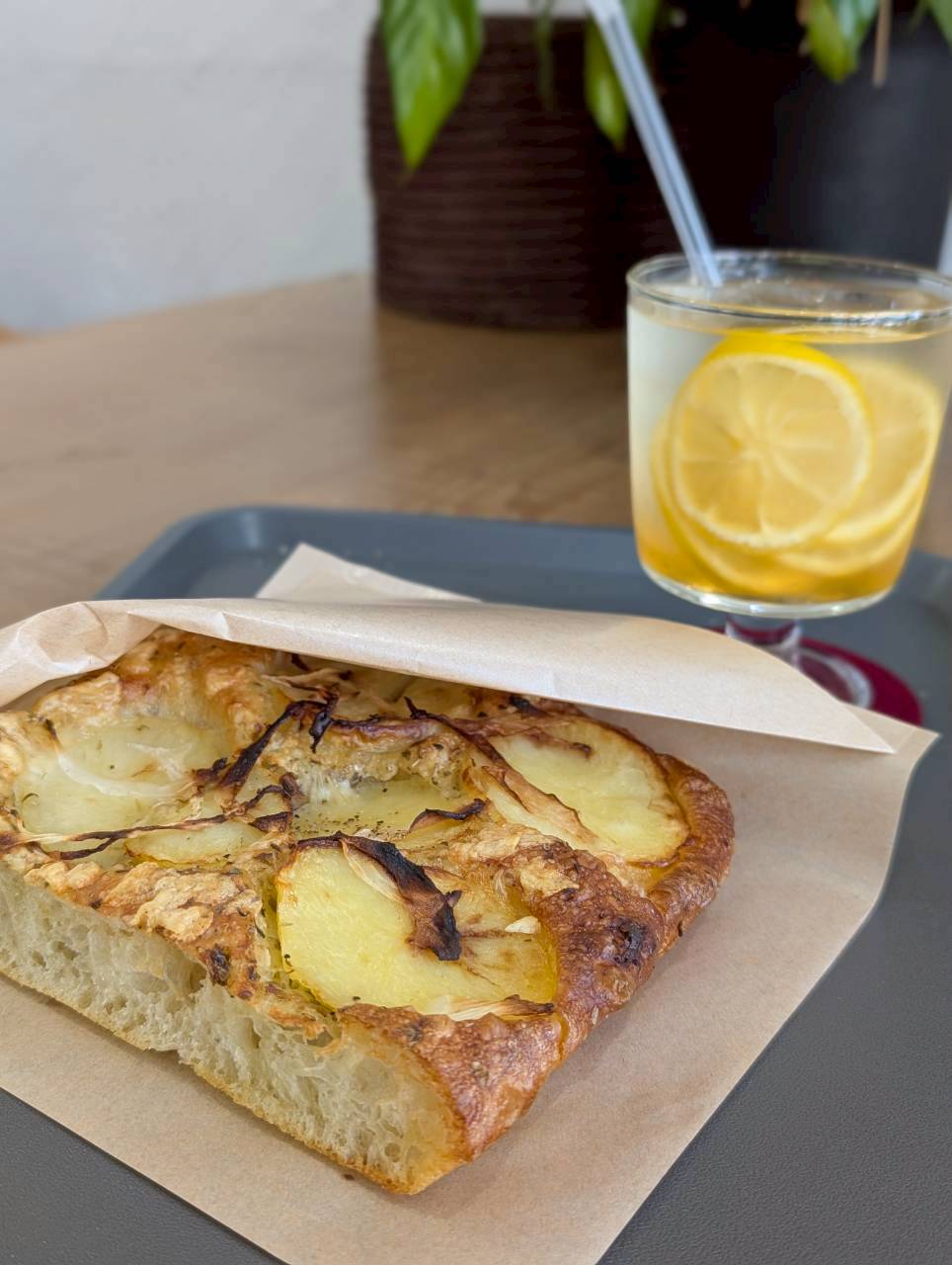Potato and onion focaccia in a parchment sleeve served with a fresh lemon iced tea — Focaccino Hakuba