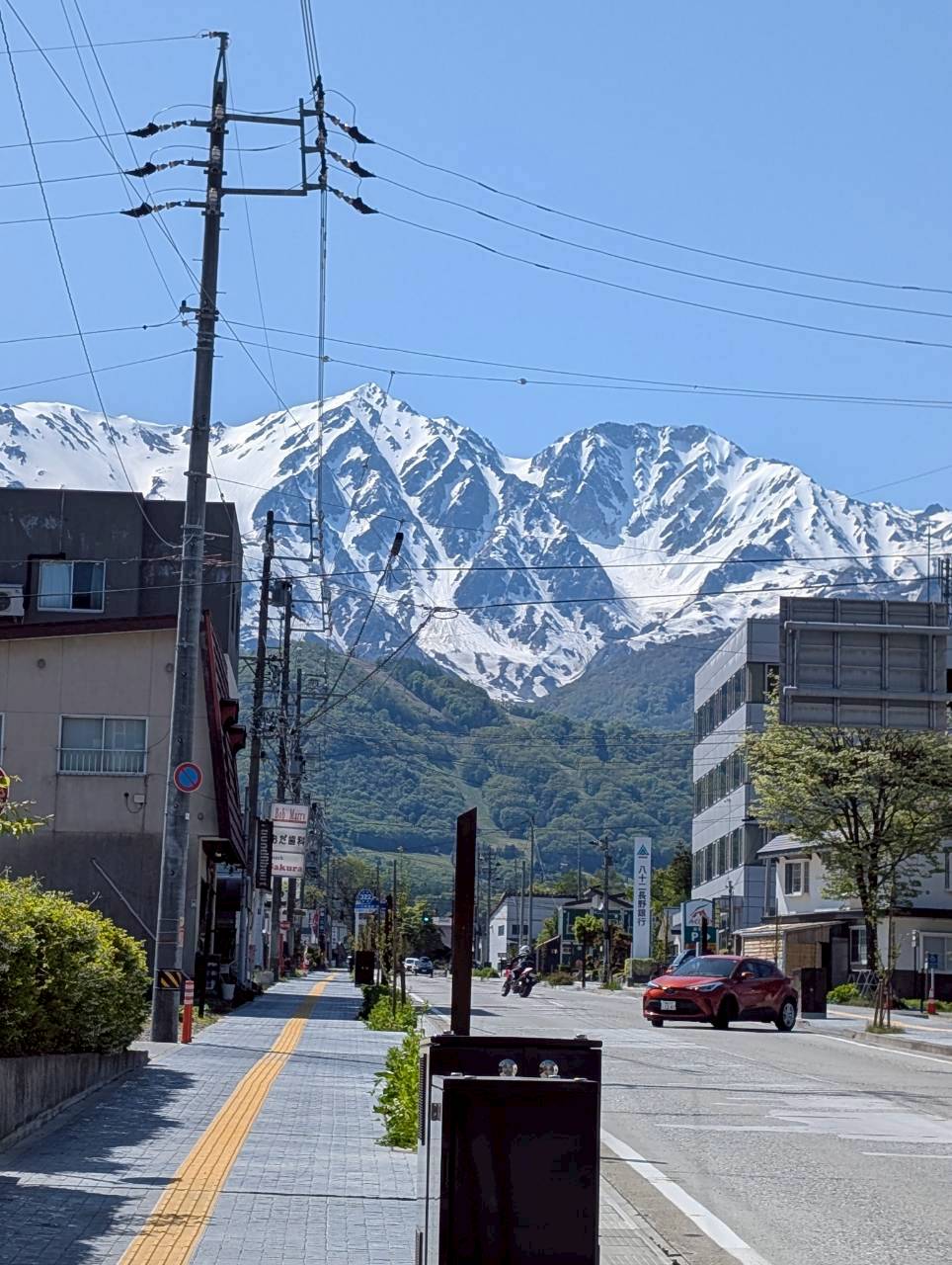 View down the street from Hakuba Station toward the snow-capped Northern Japan Alps on a clear spring day — Focaccino Hakuba